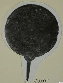 Round metal disc with a short tang handle, photographed on a white card mount, plate from Marion