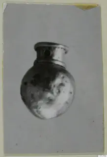 Small rounded metal object with a flared neck and a hole through the side, shown in a single photograph