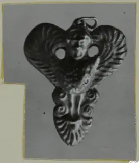 Gold pendant with a central face, fan-ribbed upper sides and spiral curls on the lower part