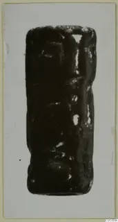 Cylinder seal from Vouni, dark stone with carved surface, photographed upright on a card mount