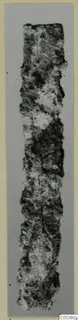 Corroded iron knife blade, shown upright, with a rough crusted surface and broken ends.