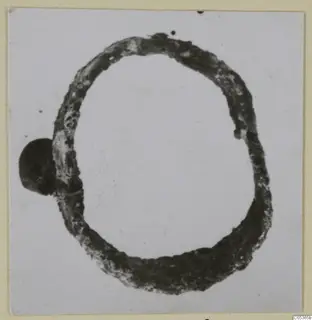 Corroded bronze ring-shaped fragment, oval in outline, with a dark rounded lump on its left side, from Amathus