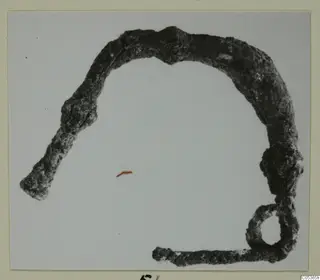 Corroded bronze personal adornment from Amathus, a bent bar with a loop at one end.