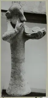 Figurine of a standing figure with one hand raised to its face and the other arm holding a flat dish-like form