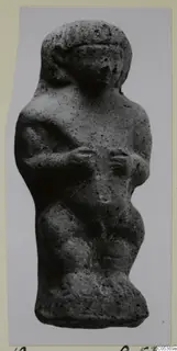Small standing figure from Amathus, grey and pitted, with arms bent across the chest and a rounded head