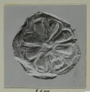 Flattened disc-shaped find from Amathus with radiating raised lines, photographed on a grey card