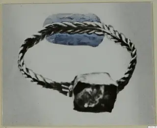 Gold jewellery fragment from Amathus: a twisted-wire loop with a blue oval element and a dark block.