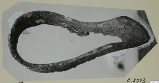 Corroded bronze object bent into a long loop, photographed on a mount, from Amathus