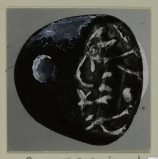 Dark oval object from Amathus T. 2-26 with pale linear pattern on one half, shown on a grey card mount