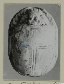 Oval object from Amathus with incised lines on its flat base, mounted on a card.