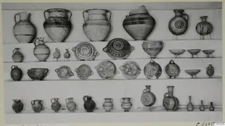 Pottery vessels set out in four rows on shelves: jugs, two-handled jars, bowls and small bottles, mostly with painted bands.