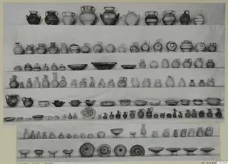 Pottery vessels from Amathus, Tomb 9, arranged in rows on a pale backdrop.