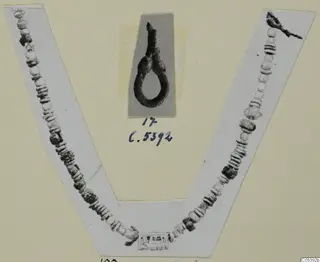 Necklace of many beads and a loop-shaped silver fragment from Amathus, shown on a photo-mount card with a handwritten number label.