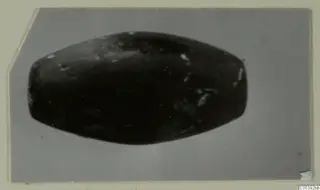 Dark elongated object from Amathus, photographed on a grey backdrop
