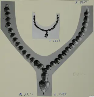 Two photographs of bead necklaces with pendants, mounted on grey and white card, one with a gold-coloured pendant at the lower point.