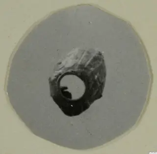 Small jewellery object with a large central hole, photographed on a round grey card