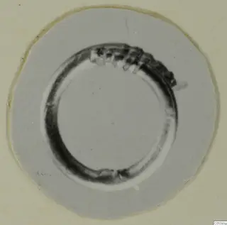 Ring from Marion, a dark circular band with a row of small notches along its upper part, photographed on a round card.