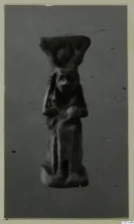Small figurine of Hator from Marion Tomb 50, standing with a wide flat headdress, shown against a grey backdrop