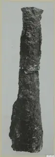 Long, heavily corroded iron weapon fragment from Amathus, standing upright against a pale grey background