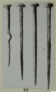 Four corroded metal nails from Marion, photographed upright side by side on a card mount.