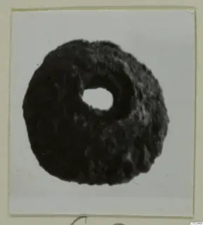 Bead from Marion: a dark, ring-shaped bead with a central hole, seen against a white background.