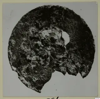 Corroded bronze disc fragment with a hole, from Marion, Tomb 9