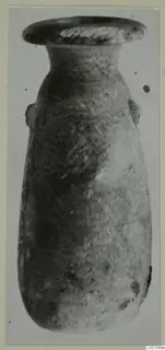 Tall narrow vessel with a flared rim and small handle lugs, photographed against a plain backdrop.