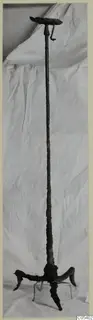 Iron object from Marion: a long corroded shaft with a flat disc-shaped top and three curved feet at the base.