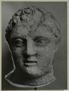 Carved stone head with short curly hair, from Mersinaki, shown frontally on a stand