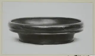 Pottery Black Glazed Ware bowl with a thick rounded rim and flaring foot, seen from the side