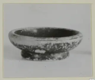 Small pottery bowl with a rounded body and low ring foot, seen from the side