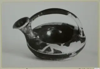 Small spouted vessel with a loop handle, dark glaze and pale painted pattern on the body