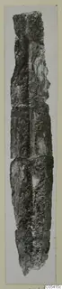 Long, narrow, heavily corroded metal object from Amathus, photographed upright on a card mount.