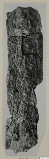 Long, narrow, heavily corroded iron object photographed upright on a grey mount, Amathus tomb find
