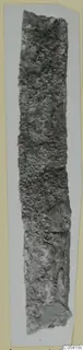 Long, narrow iron tool from Amathus, heavily corroded and encrusted, shown upright on a grey card.