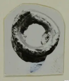 Silver ring from Marion Tomb 26, heavily corroded, shown in a photograph on a card mount
