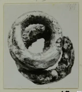 Silver ring from Marion Tomb 26, corroded, shown in a mounted photograph