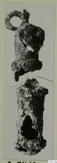 Two corroded silver objects, one with a ring-shaped loop at the top, on a mounted print.