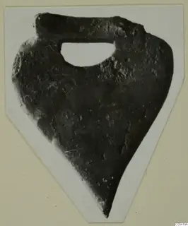 Dark, corroded bronze plaque with a hole below its upper band, from Marion Tomb 58