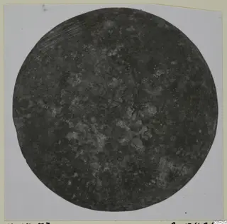 Corroded bronze disc from Marion, photographed flat on a light card.