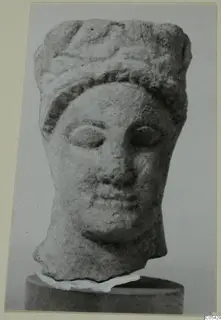 Limestone head from Mersinaki with wavy hair or headdress and large almond-shaped eyes, shown on a cylindrical base