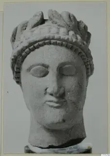 Carved limestone head from Mersinaki, wearing a tall crown of leaf-like forms above a band of dotted ornament.