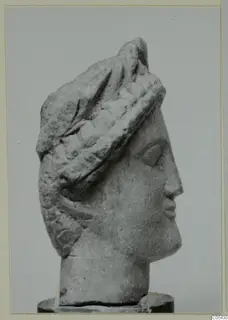 Limestone head from Mersinaki, shown in right profile with a tall layered headdress on a dark base.