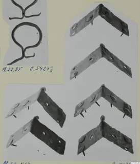 Bronze angle-shaped mountings with rivet heads and nails on a mounted card, with bent wire pieces at top left