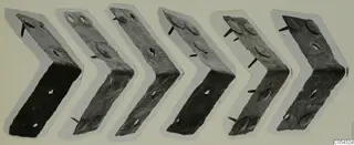 Six bent metal plates with protruding nails from Marion, arranged in a row on pale card.