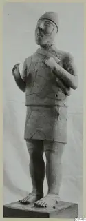 Terracotta statue of a standing figure with a close-fitting cap, short skirt and bare feet, on a wooden base