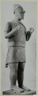 Terracotta statue of a standing male figure in a cap and fringed skirt, from Ayia Irini