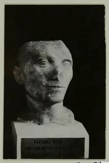 Roman sculpture: marble head with short hair on a white plinth, against a dark background