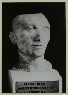 Stone head sculpture on a square block base, with a printed plaque on the front of the base.