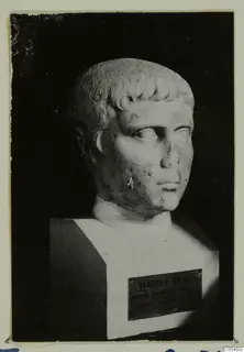 Roman sculpture: a stone head and bust with short curled hair, photographed against a dark background